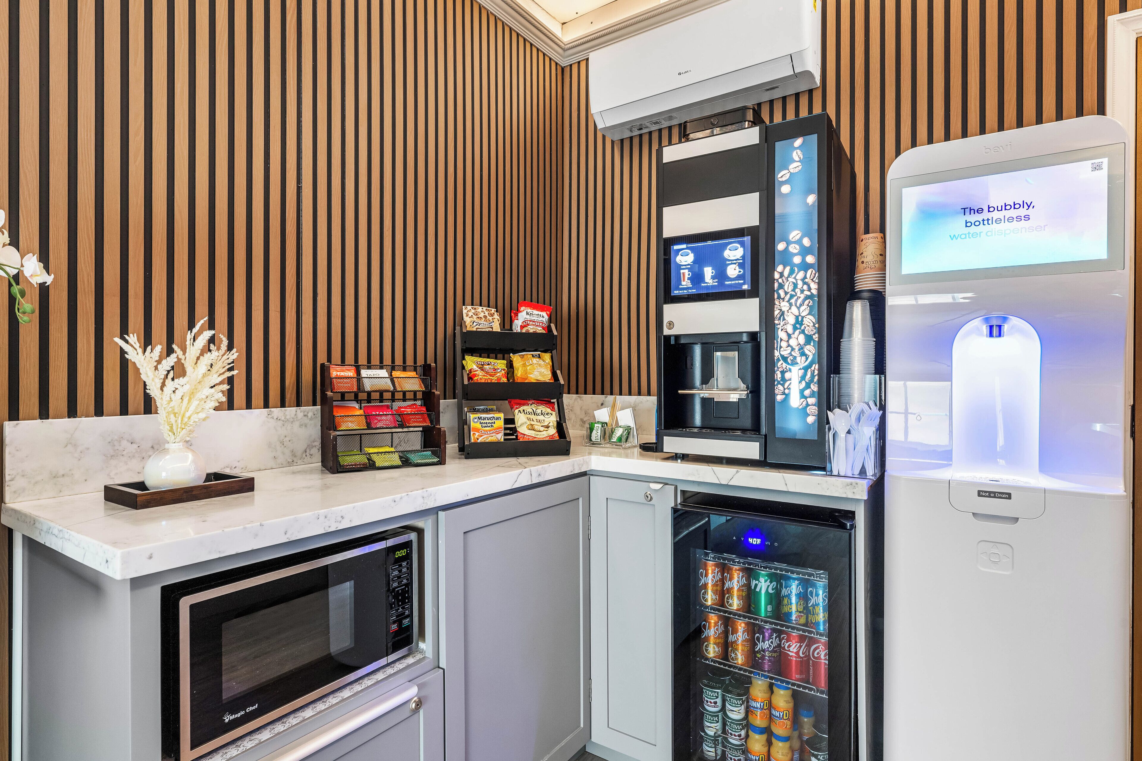 A modern kitchen with a built-in microwave, a water dispenser, and a beverage fridge.