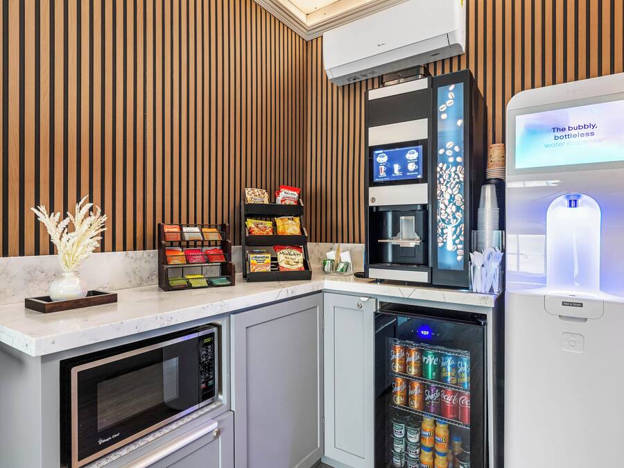A modern kitchen with a built-in microwave, a water dispenser, and a beverage fridge.