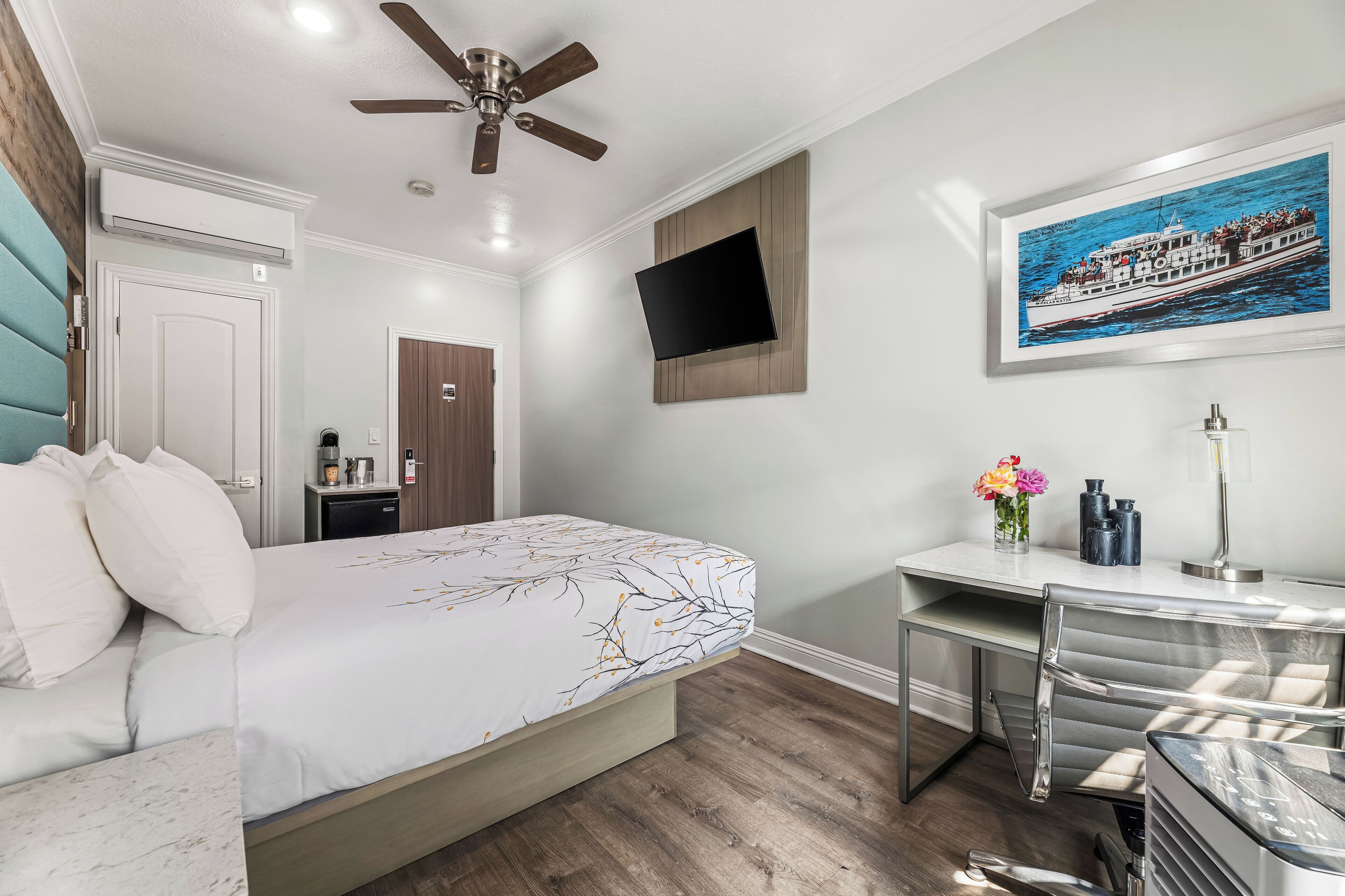 Une chambre d’hôtel moderne équipée d’un lit, d’un bureau et d’un téléviseur fixé au mur.