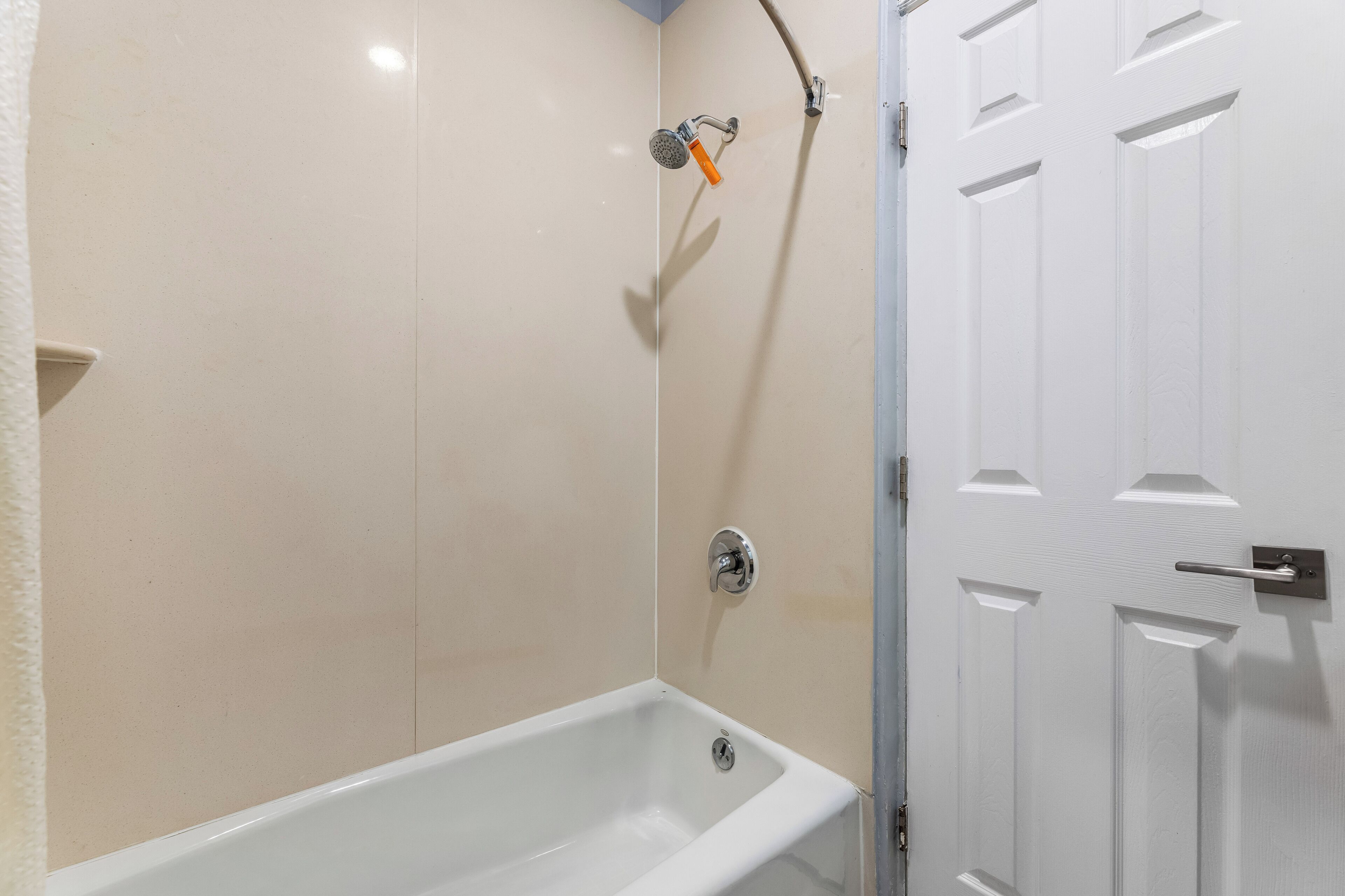 A bathroom with a bathtub, a shower, and a white door.