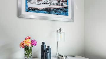 Un bureau orné d’un tableau encadré représentant un bateau, d’un vase de fleurs et d’une lampe de bureau.