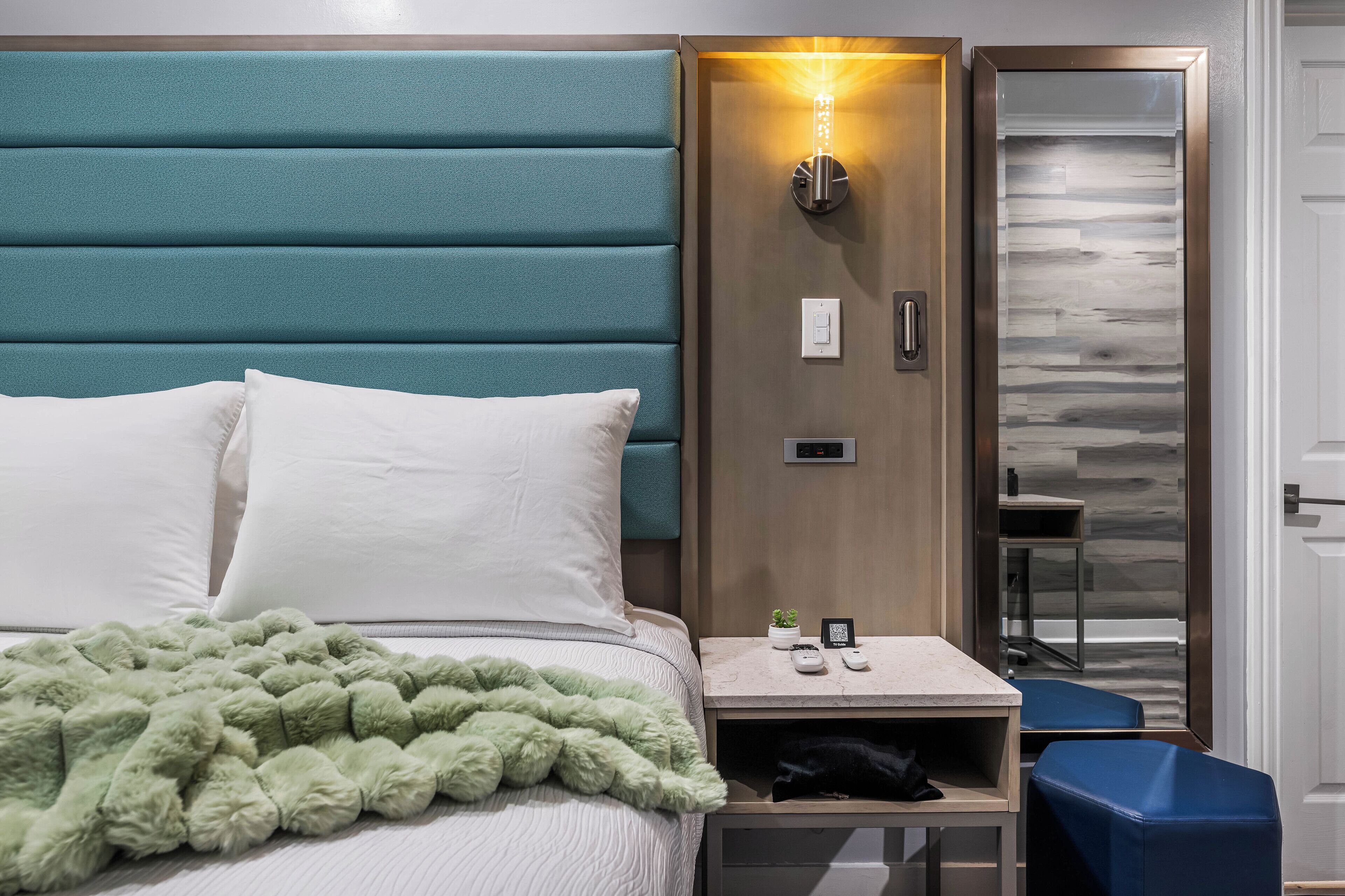 Een hotelkamer met een bed, nachtkastje, bureau en stoel.