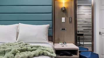 Een hotelkamer met een bed, nachtkastje, bureau en stoel.