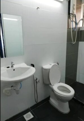 Un baño con lavamanos blanco, inodoro y zona de ducha.
