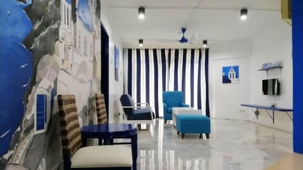 Ein modernes Wohnzimmer mit Wandmalerei aus Stein, einem Streifen-Vorhang, einem blauen Sessel, einem weißen Sofa und einem kleinen Tisch.