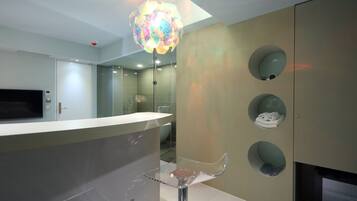 A modern bathroom with a curved vanity, a glass shower enclosure, and a unique ceiling light fixture.