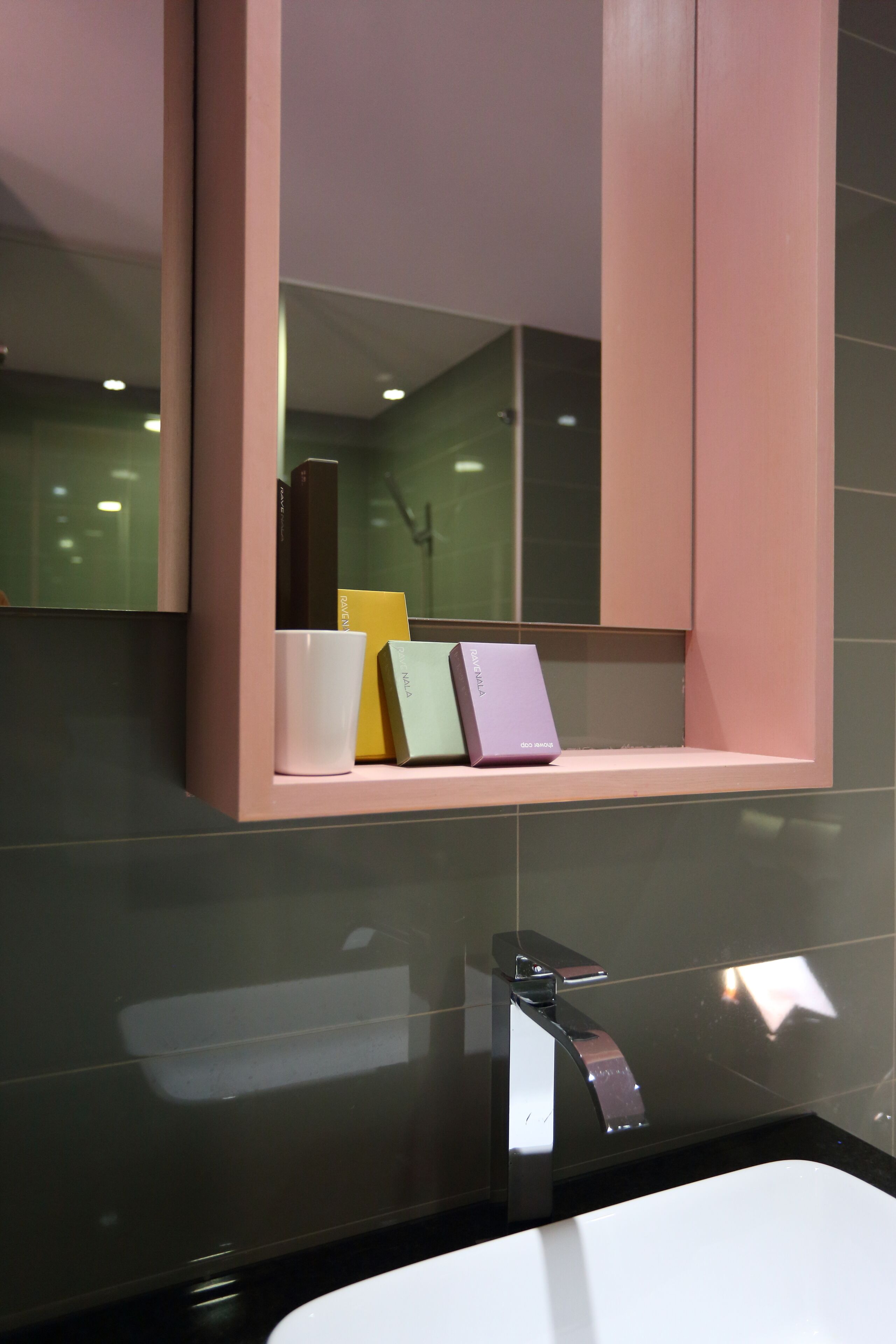 A modern bathroom with a large mirror, a white sink, and a chrome faucet.