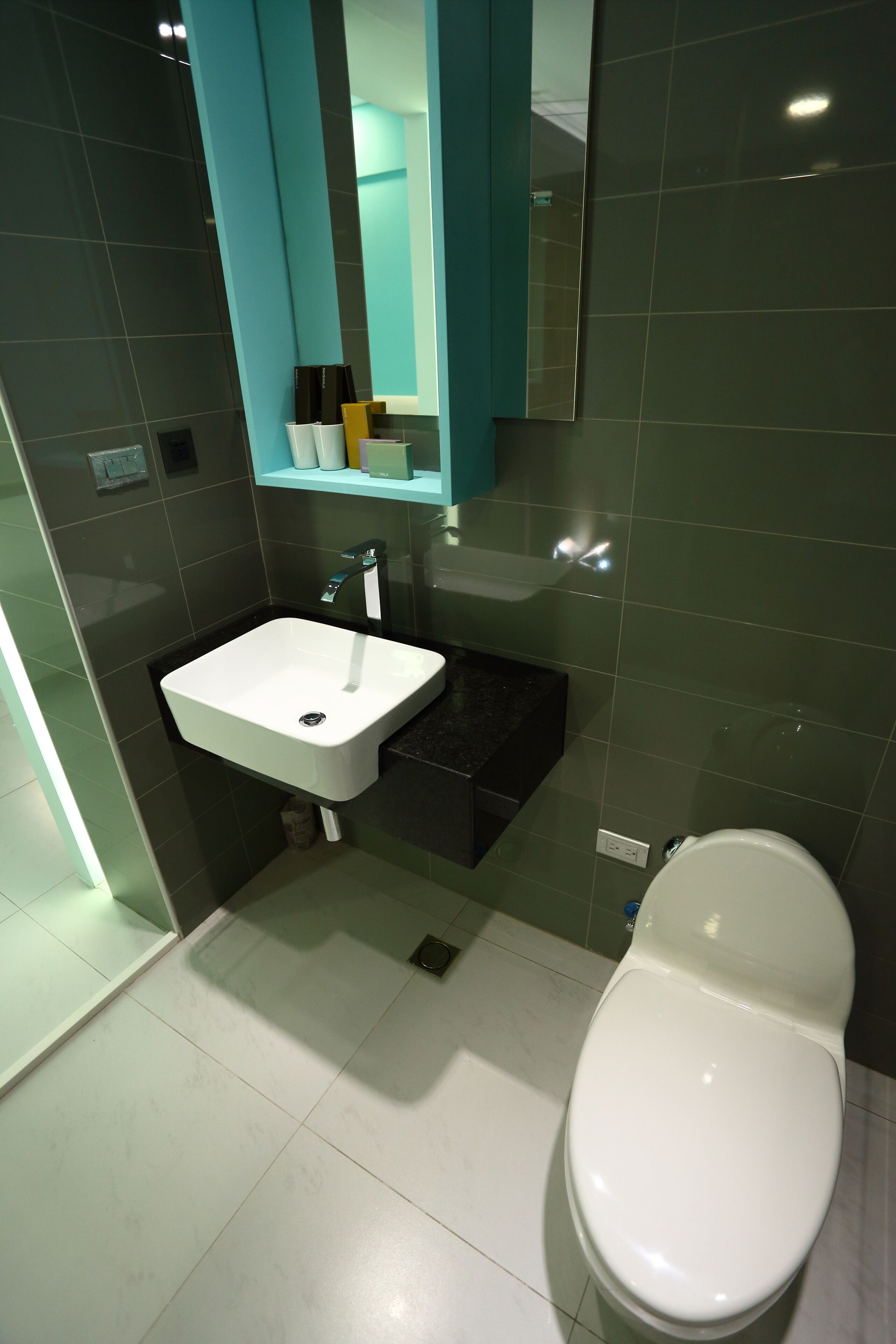 A modern bathroom with a white sink, a mirror, and a toilet.
