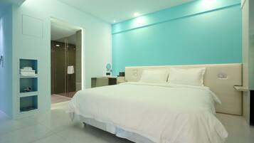 Una camera d'albergo moderna con un letto grande, un cabina armadio e un bagno con doccia in vetro.