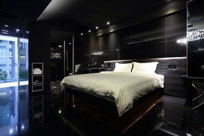 A modern bedroom with a large bed, a nightstand, a mirror, and a view of the outside. - The Fantasy Apartment (Hualien City)