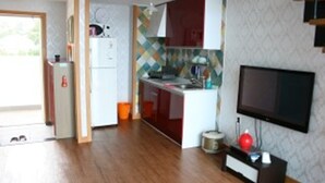Eine kompakte Küche mit Kühlschrank, Herd und Spüle, einem Flachbildfernseher und einer gemusterten Spritzschutzwand.