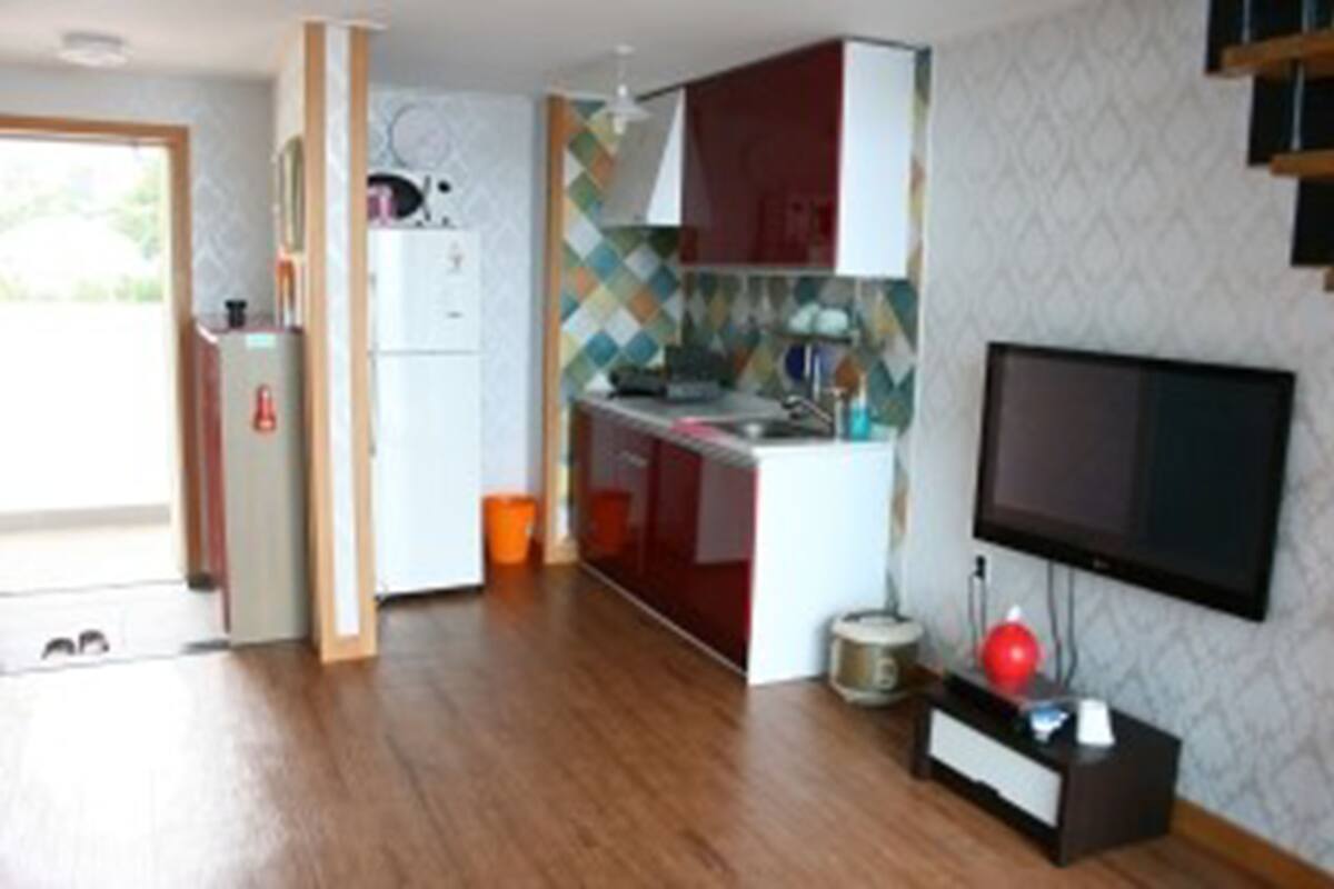 Une cuisine compacte équipée d’un réfrigérateur, d’une cuisinière et d’un évier, ainsi que d’un téléviseur à écran plat et d’un crédence décorée.