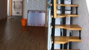 Ein geräumiger Raum mit einer Holztreppe, einem Deckenventilator und einer gefliesten Wand.