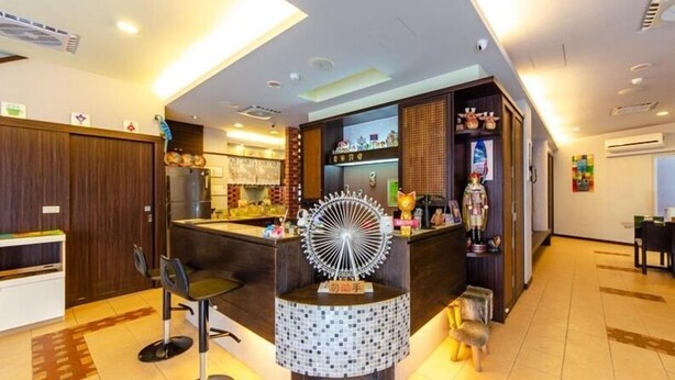 A modern hotel lobby with a reception desk, a bar area, and a seating area with a unique circular light fixture. - Chamie B&B (Hengchun)