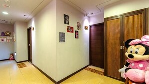 A hotel hallway with a Minnie Mouse statue, a wooden door, and several framed pictures on the wall. - Chamie B&B (Hengchun)