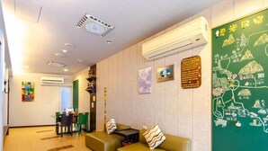 A hotel lobby with a reception desk, seating area, and a green wall with a map. - Chamie B&B (Hengchun)