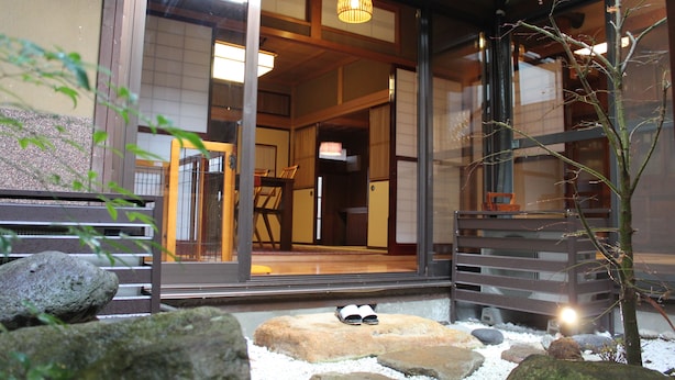 A traditional Japanese building with sliding doors, a wooden deck, and a stone pathway leading to the entrance. - K's Villa Hida-an (Takayama)