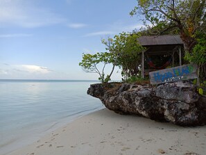 A wooden signboard for Hoga Island Resort on a rocky outcrop by a beach. - Hoga Island Dive Resort Wakatobi (Hoga Island)