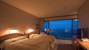 A hotel room with two beds, a desk, a TV, and a balcony with a view of the city. - Ginrinsou (Otaru)