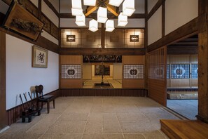 Una habitación tradicional japonesa con suelo de tatami, una mesa de madera baja y un farol colgante.
