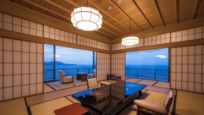 A traditional Japanese room with tatami flooring, a low table, a sofa, and a view of the sea. - Ginrinsou (Otaru)