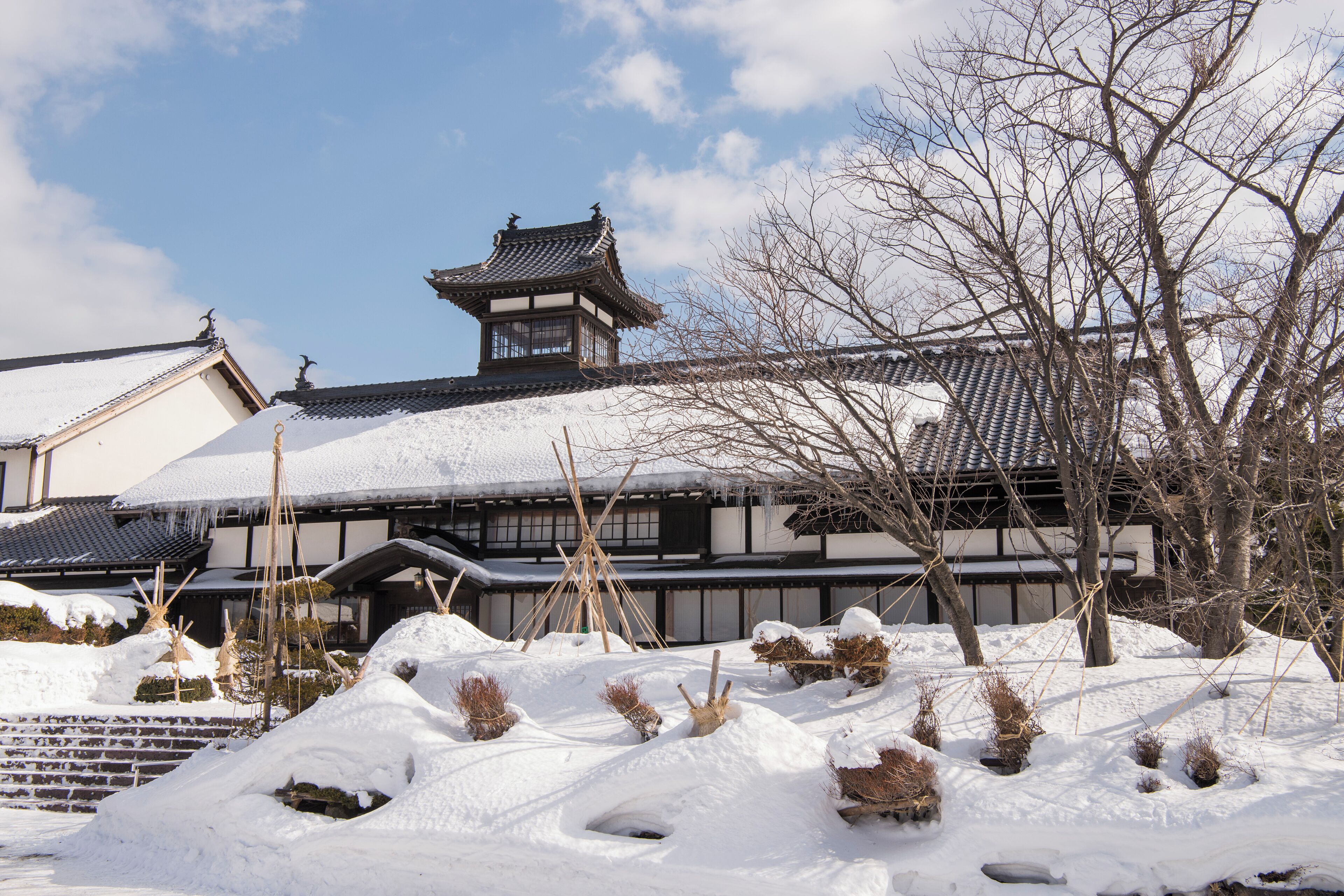 Un edificio tradicional japonés con tejado de tejas, vigas de madera y una pequeña estructura parecida a una torre.