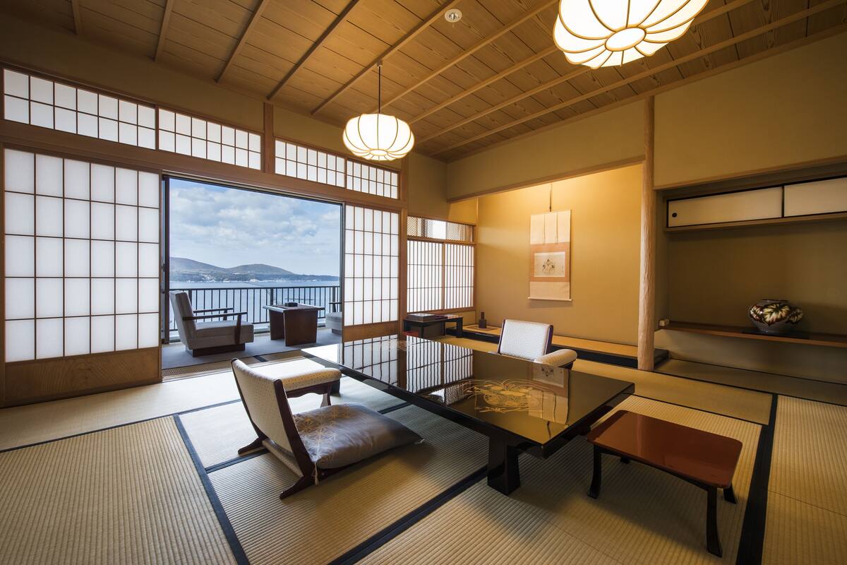 A traditional Japanese room with tatami flooring, low tables, and sliding doors.