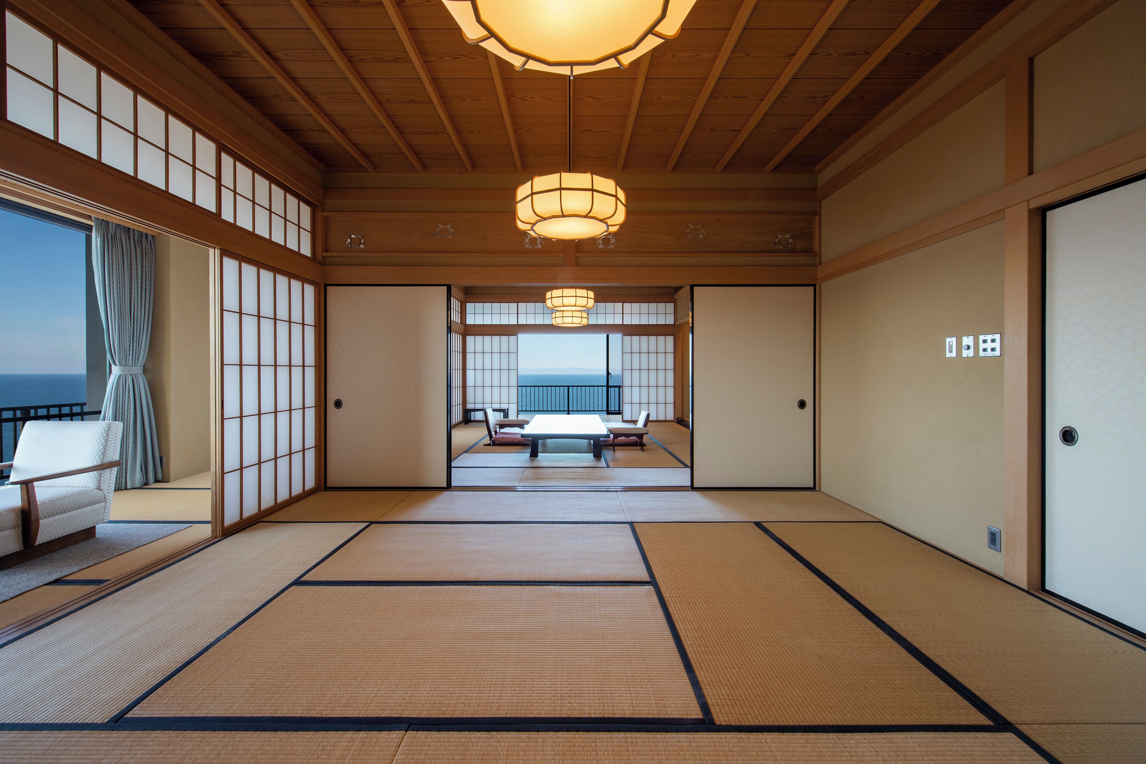 A traditional Japanese room with tatami flooring, sliding doors, and a view of the sea.