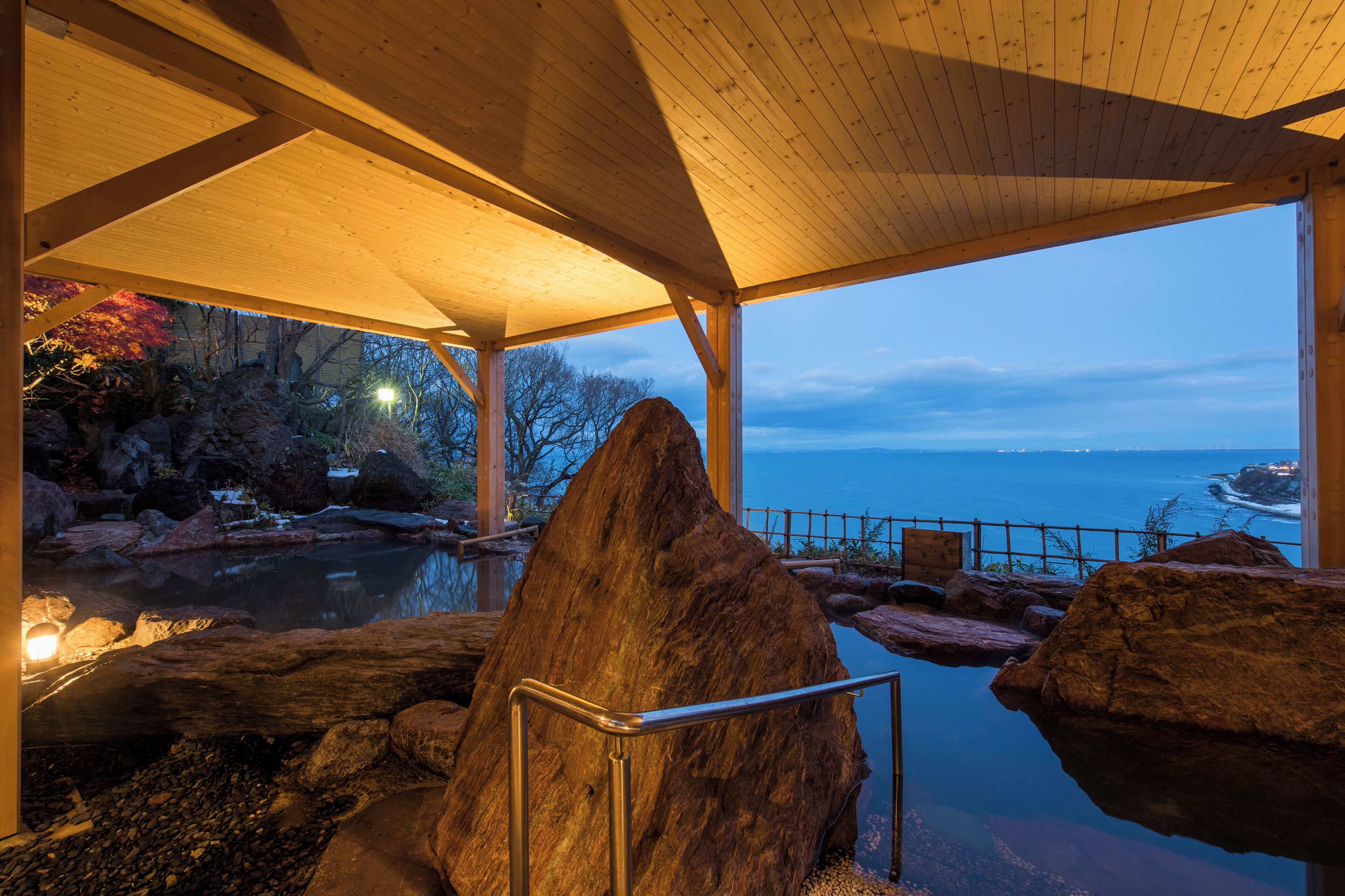 A wooden pavilion with a view of a body of water and rocky terrain.