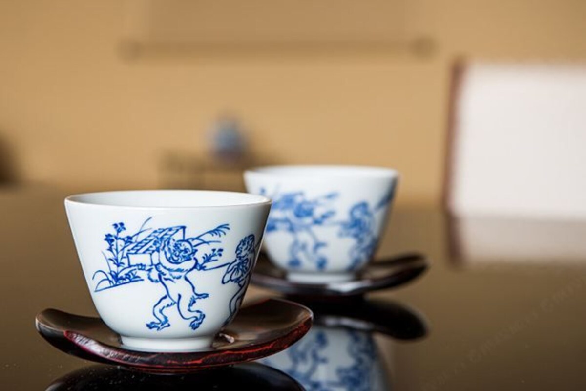 Two ceramic cups with blue floral designs on a reflective surface.