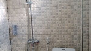 A small bathroom with a shower, toilet, and a wall-mounted faucet. - Wakatobi Dive Inn (Kaledupa Island)