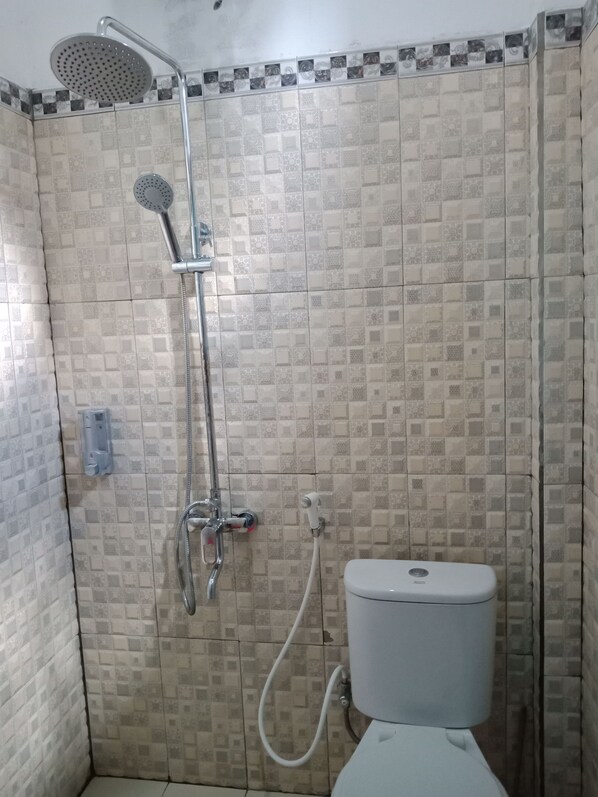 A small bathroom with a shower, toilet, and a wall-mounted faucet. - Wakatobi Dive Inn (Kaledupa Island)
