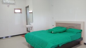 A bedroom with a bed, a bedside table, a mirror, and a window. - Wakatobi Dive Inn (Kaledupa Island)