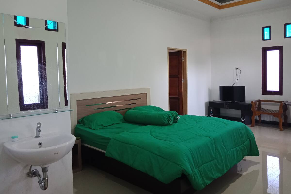 A bedroom with a bed, a bedside table, a TV, and a wardrobe.