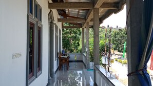 A covered corridor with a polished floor, wooden chairs, and a view of greenery outside. - Wakatobi Dive Inn (Kaledupa Island)