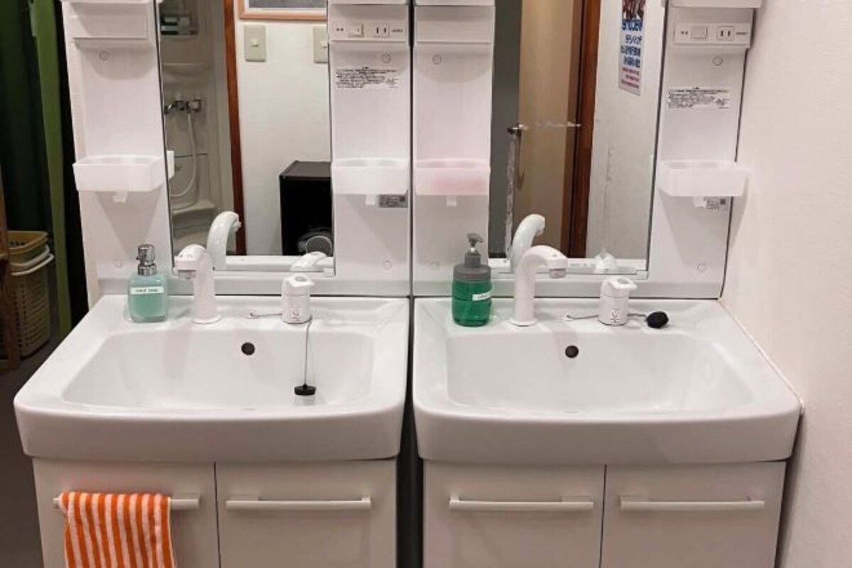 A bathroom with two sinks, each with a mirror above, and a towel rack with an orange towel.