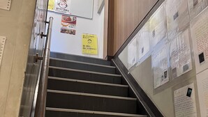 A staircase with metal handrails and wooden steps, leading to a room with a whiteboard and various notices. - Guesthouse LuLuLu (Kochi)
