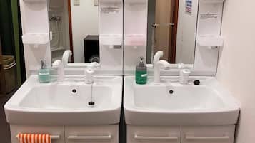 A bathroom with two sinks, each with a mirror above. There are hand soap dispensers and a towel rack with an orange towel.
