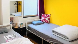 A room with a bed, bedside table, lamp, and a window with curtains. - Guesthouse LuLuLu (Kochi)