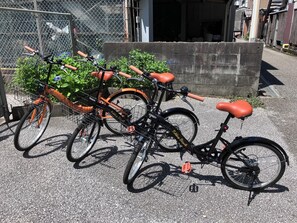 A bicycle parked in front of a building with a chain-link fence and a concrete wall. - Guesthouse LuLuLu (Kochi)