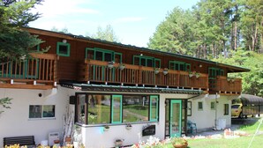A wooden chalet with a balcony, large windows, and a garden area with flowers. - Hirotani Pension & Lodge (Hara)