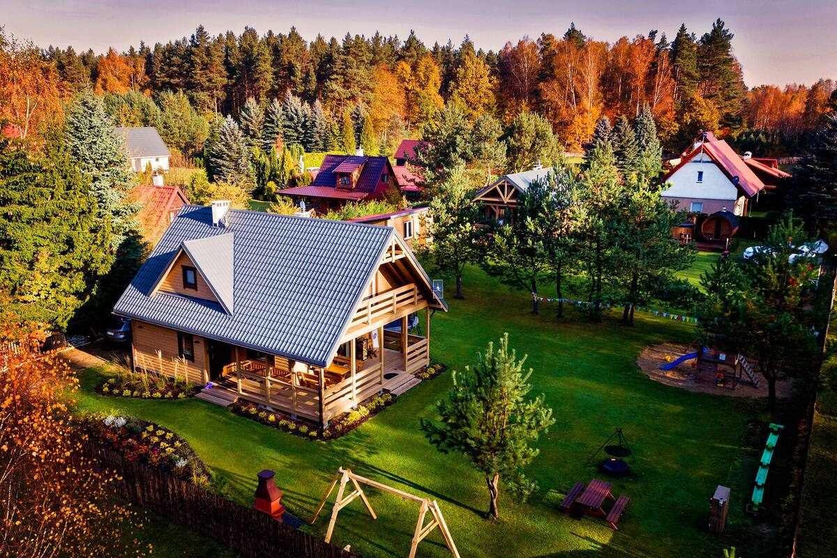 Une cabane en bois avec un toit en pente, entourée d’une pelouse bien entretenue et d’arbres.