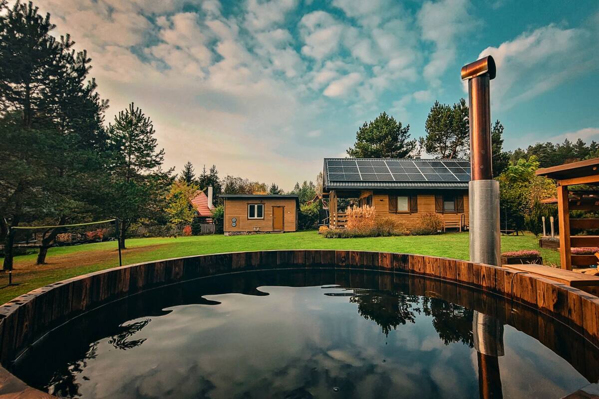 Une maison dotée d’un toit recouvert de panneaux solaires, d’une piscine et d’une terrasse en bois.