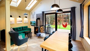 A modern interior with a green sofa, wooden dining table, and a fireplace. - Winiec Family Houses (Winiec)