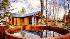 A wooden cabin with a large outdoor hot tub, surrounded by trees and a clear sky. - Winiec Family Houses (Winiec)