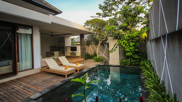 A modern house with a swimming pool, lounge chairs, and a TV in the living area. - Giri Ungasan Villa (Ungasan)
