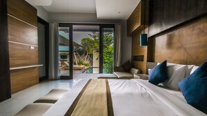 A modern hotel room with a large bed, a sofa, and a view of a pool and outdoor area. - Giri Ungasan Villa (Ungasan)