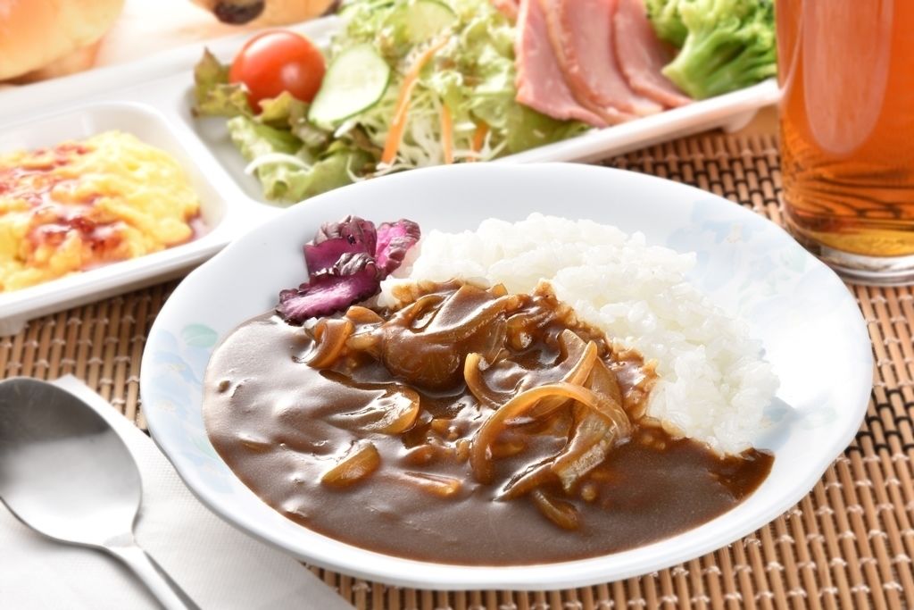 A plate of food with rice and a brown sauce, accompanied by a salad and a glass of tea.
