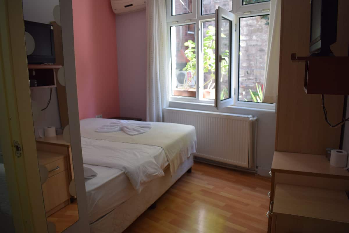 Une chambre à coucher avec un lit, une fenêtre, un radiateur et un plancher en bois.