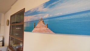 A room with a large painting of a wooden pier leading to a calm sea. - Spacious Apartment - 5-7 minute walk to Shinkansen and Shin-Kobe Subway Station (Kobe)